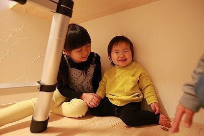 自然素材で増築した子供部屋のデスク下に潜り込み、秘密基地のように遊ぶお子さん。